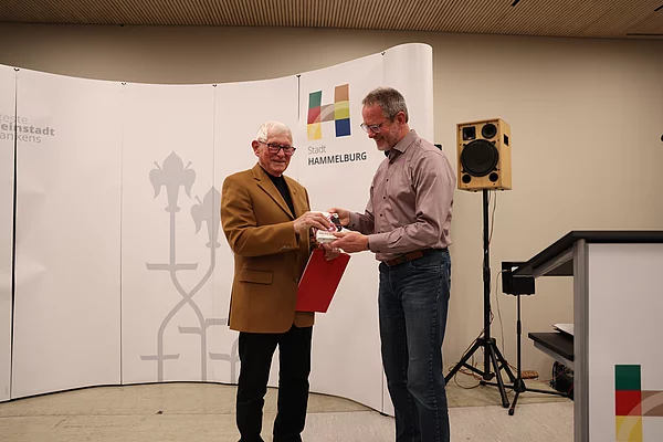 Geschenkübergabe von Martin Stapper an Winfried Laske für das jährliche Reimen der Ehrungen an die Stillen Helfer und Helferinnen.